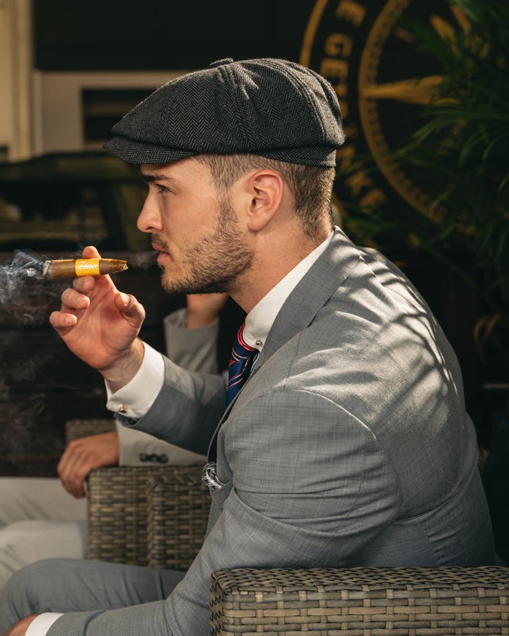 Andreas Schmid, flat cap, grey suit and a cigar