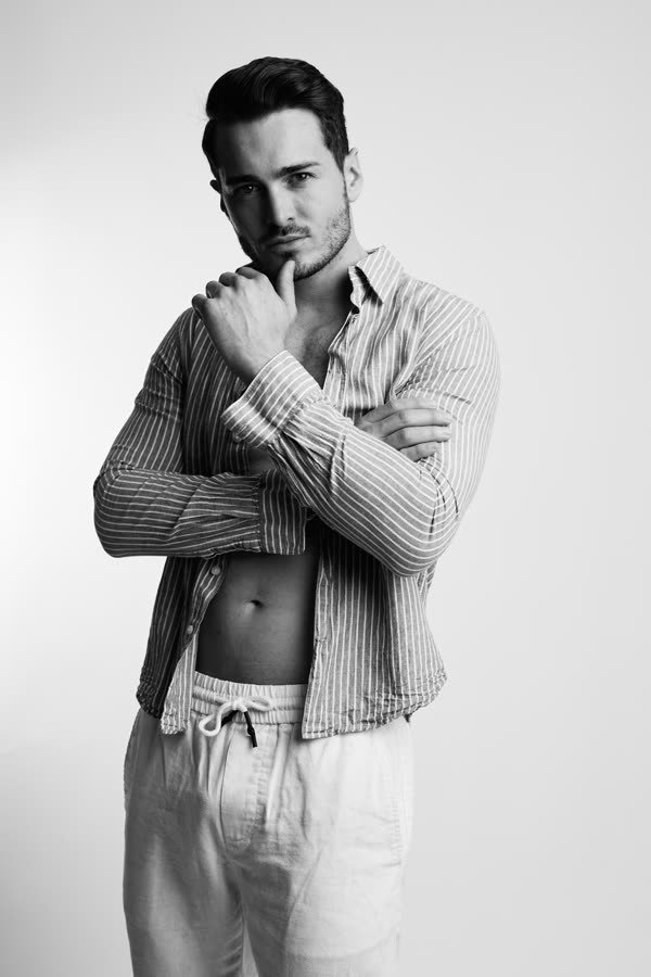 Andreas Schmid, black and white studio photo in an open striped shirt