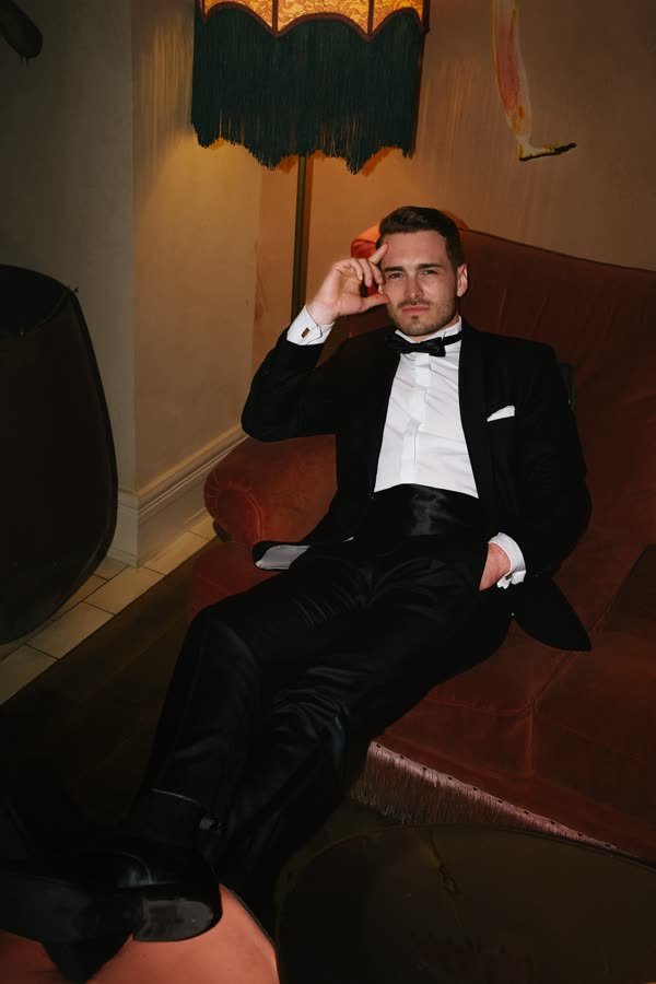 Andreas Schmid, tuxedo on a red sofa