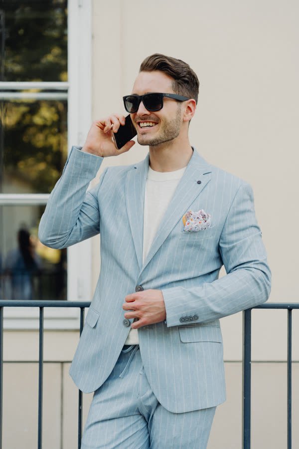 Andreas Schmid, light blue suit and sunglasses, on the phone